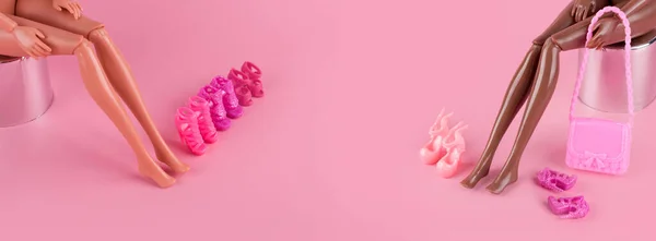 Pernas magras longas de bonecas de brinquedo plásticas e sapatos elegantes em fundo rosa. Bonecas de plástico experimentando sapatos de salto alto. Escolhendo sapatos novos. Venda, moda e compras, conceito de amizade feminina. — Fotografia de Stock