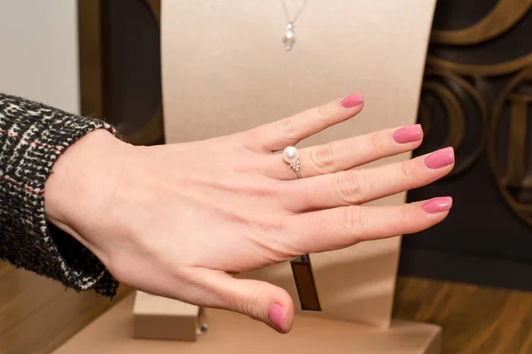 Young woman choosing ring in jewelry store. Hand of female customer in jewelry shop. Trying a diamond ring with white pearl, fashion and buying concept — Stock Photo, Image