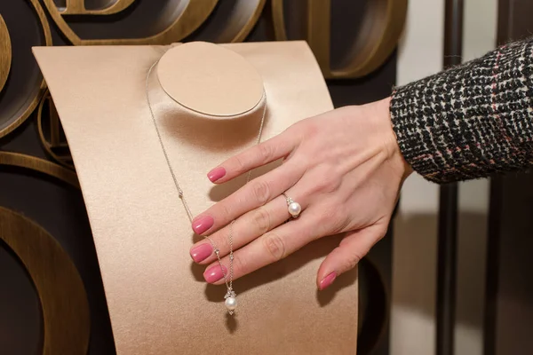 Young woman choosing ring in jewelry store. Hand of female customer in jewelry shop. Trying a diamond ring with white pearl, fashion and buying concept — Stock Photo, Image