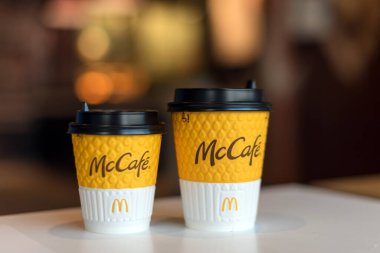 Kyiv, Ukrayna - 12 Ekim 2020: McDonald 's ve McCafe logosu olan iki kağıt bardak McDonald' s restoranının arka planındaki pencerenin yanındaki masada. Seçici odak.