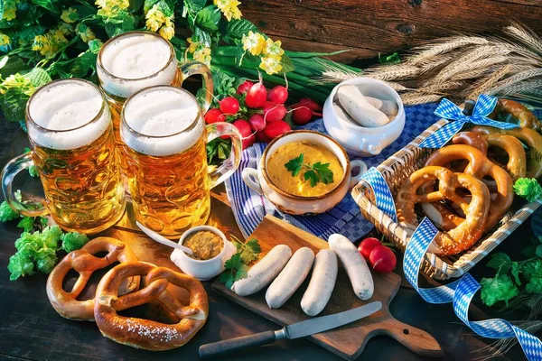 Bavarian sausages with pretzels, sweet mustard and beer mugs on rustic wooden table