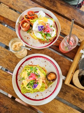 İki dilim ekşi ekmek, avokado ezmeli, karabiberli ve yumurtalı beyaz yengeç etli. Beyaz bir tabakta limon dilimi