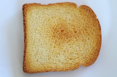 Kahvaltı veya diğer öğünler için hazır beyaz bir tabaktabaktabakta çıtır bir dilim tost ekmeğinin yakın çekim.