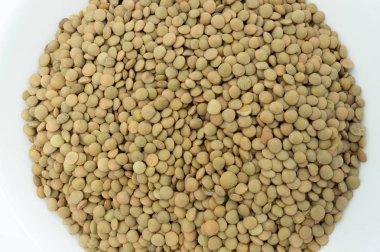 Beyaz arkaplanda pişirilmemiş mercimek yığını.