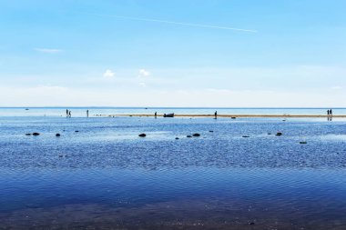 people walk on the shallows of the Bay at low tide clipart