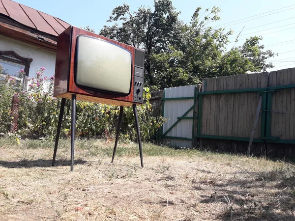Özel bir evin avlusunda bacaklarında eski bir televizyon.