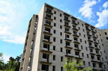 Mavi gökyüzünün altındaki terk edilmiş yüksek katlı bir binanın fotoğrafı..