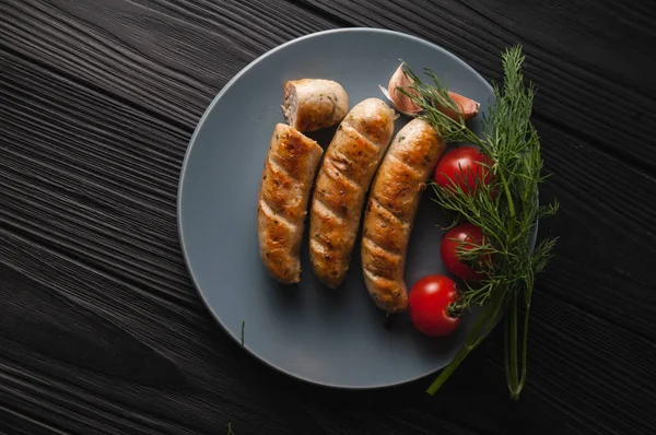 Drie Gegrilde Worstjes Een Grijze Plaat Een Houten Zwarte Achtergrond — Stockfoto