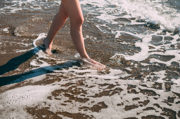Young girl runs along the sea sandy beach barefoot, concept, legs