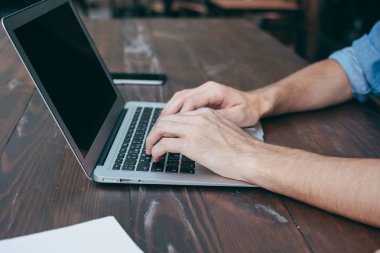 Erkekler ellerini ücretsiz Wi-Fi, bir defter ön planda bir kafede ahşap bir kahverengi masa üstünde a laptop basılır. Bir çevirmen için kavram zaman, her yerde çalışır. Yan görünüm, kavram