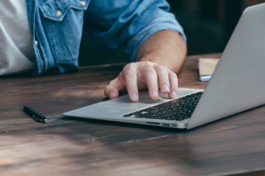 Erkekler ellerini ücretsiz Wi-Fi, bir defter ön planda bir kafede ahşap bir kahverengi masa üstünde a laptop basılır. Bir çevirmen için kavram zaman, her yerde çalışır. Yan görünüm, kavram