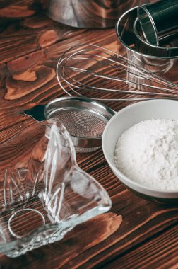 Maddeler de yalan çırpma teli tam un için üç tavuk yumurtası ve kayrak Sedye nerede yemeklerinde ahşap bir kahverengi masa üzerinde. Yukarıdan görüntüleyin. Metnin altında yer