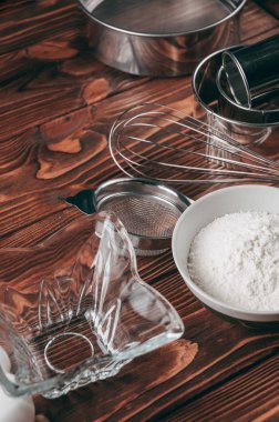 Maddeler de yalan çırpma teli tam un için üç tavuk yumurtası ve kayrak Sedye nerede yemeklerinde ahşap bir kahverengi masa üzerinde. Yukarıdan görüntüleyin. Metnin altında yer