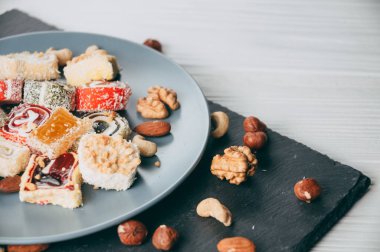 Geleneksel oryantal tatlılar ve fındık: fındık, kaju fıstığı Beyaz ahşap zemin üzerinde. Türk tatlı dönüm odağı olduğunu. Yukarıdan görüntüleyin. Metnin altında yer