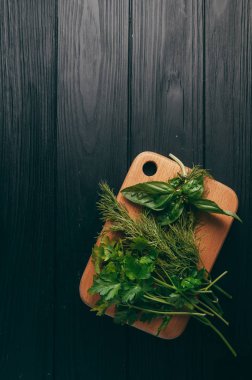 Otlar ve baharatlar bir gemide ahşap kahverengi, siyah ahşap zemin. Maydanoz dereotu. Yemek pişirmek için malzemeler. Üstten görünüm, altında metni metso