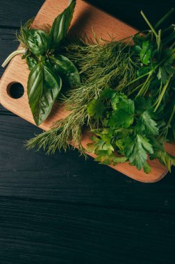 Otlar ve baharatlar bir gemide ahşap kahverengi, siyah ahşap zemin. Maydanoz dereotu. Yemek pişirmek için malzemeler. Üstten görünüm, altında metni metso