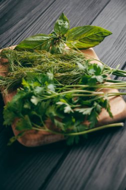 Otlar ve baharatlar bir gemide ahşap kahverengi, siyah ahşap zemin. Maydanoz dereotu. Yemek pişirmek için malzemeler. Üstten görünüm, altında metni metso