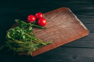 Domates, maydanoz ve dereotu bir ahşap kesme tahtası siyah ahşap zemin üzerinde. Görünüm sperm hücrelerinin altında metin yerleştirin