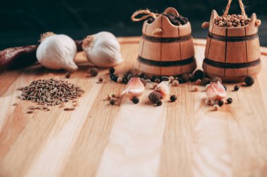 Baharatlar: kırmızı biber, kara biber, sarımsak, kimyon, kişniş, tatlı biber yalan bir kahverengi ahşap tahta siyah bir tablo üzerinde yuvarlak. Metnin altında yer