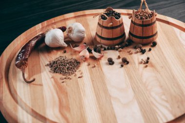 Baharatlar: kırmızı biber, kara biber, sarımsak, kimyon, kişniş, tatlı biber yalan bir kahverengi ahşap tahta siyah bir tablo üzerinde yuvarlak. Metnin altında yer