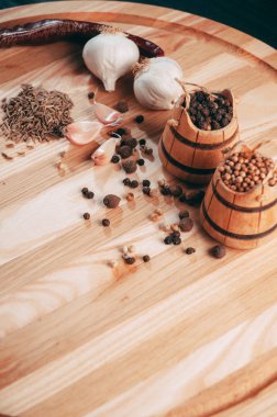 Baharatlar: kırmızı biber, kara biber, sarımsak, kimyon, kişniş, tatlı biber yalan bir kahverengi ahşap tahta siyah bir tablo üzerinde yuvarlak. Metnin altında yer