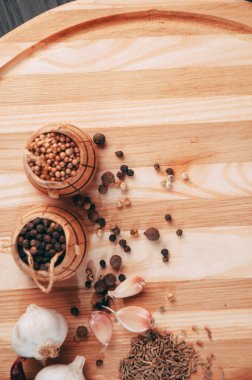 Baharatlar: kırmızı biber, kara biber, sarımsak, kimyon, kişniş, tatlı biber yalan bir kahverengi ahşap tahta siyah bir tablo üzerinde yuvarlak. Metnin altında yer