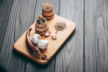 Baharatlar: kırmızı biber, kara biber, sarımsak, kimyon, kişniş, tatlı biber yalan bir kahverengi ahşap tahta üzerinde siyah bir tablo üzerine. Metnin altında yer