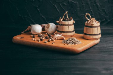 Baharatlar: kırmızı biber, kara biber, sarımsak, kimyon, kişniş, tatlı biber yalan bir kahverengi ahşap tahta üzerinde siyah bir tablo üzerine. Metnin altında yer