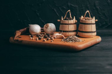 Baharatlar: kırmızı biber, kara biber, sarımsak, kimyon, kişniş, tatlı biber yalan bir kahverengi ahşap tahta üzerinde siyah bir tablo üzerine. Metnin altında yer