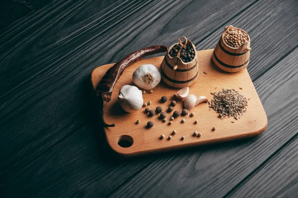 Baharatlar: kırmızı biber, kara biber, sarımsak, kimyon, kişniş, tatlı biber yalan bir kahverengi ahşap tahta üzerinde siyah bir tablo üzerine. Metnin altında yer