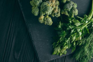 Koyu ahşap tablo, taze yeşil brokoli, maydanoz, dereotu sağlığınız için üzerinde. Flatlay. Tarifi. Malzemeler. Diyet yiyecek. Metnin altında yer