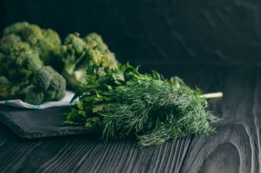 Koyu ahşap tablo, taze yeşil brokoli, maydanoz, dereotu sağlığınız için üzerinde. Flatlay. Tarifi. Malzemeler. Diyet yiyecek. Metnin altında yer