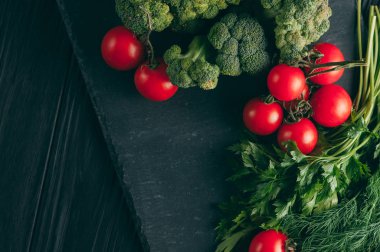 Koyu ahşap bir masa, taze yeşil brokoli, maydanoz, dereotu ve kiraz domates sağlığınız için üzerinde. Tarifi. Malzemeler. Diyet yiyecek. Metnin altında yerleştirin. Üstten görünüm