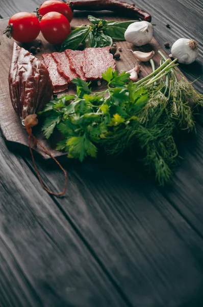 Geräucherte Salami Auf Einem Schwarzen Tisch Und Einem Braunen Brett — Stockfoto