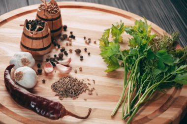 Baharatlar: kırmızı biber, kara biber, sarımsak, kimyon, kişniş, tatlı biber yalan bir kahverengi ahşap tahta siyah bir tablo üzerinde yuvarlak. Metnin altında yer