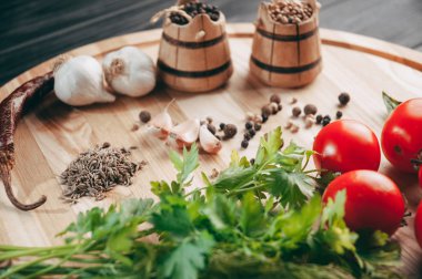 Baharatlar: kırmızı biber, kara biber, sarımsak, kimyon, kişniş, tatlı biber yalan bir kahverengi ahşap tahta siyah bir tablo üzerinde yuvarlak. Metnin altında yer