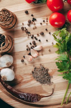 Baharatlar: kırmızı biber, kara biber, sarımsak, kimyon, kişniş, tatlı biber yalan bir kahverengi ahşap tahta siyah bir tablo üzerinde yuvarlak. Metnin altında yer