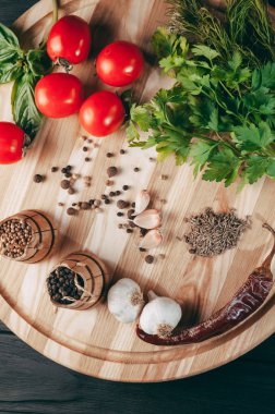 Baharatlar: kırmızı biber, kara biber, sarımsak, kimyon, kişniş, tatlı biber yalan bir kahverengi ahşap tahta siyah bir tablo üzerinde yuvarlak. Metnin altında yer