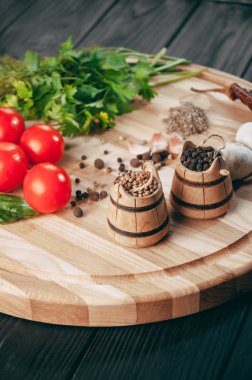 Baharatlar: kırmızı biber, kara biber, sarımsak, kimyon, kişniş, tatlı biber yalan bir kahverengi ahşap tahta siyah bir tablo üzerinde yuvarlak. Metnin altında yer