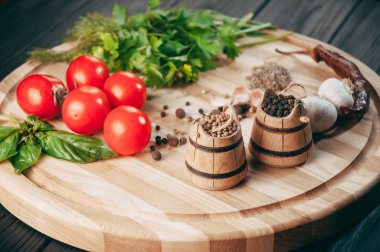 Baharatlar: kırmızı biber, kara biber, sarımsak, kimyon, kişniş, tatlı biber yalan bir kahverengi ahşap tahta siyah bir tablo üzerinde yuvarlak. Metnin altında yer