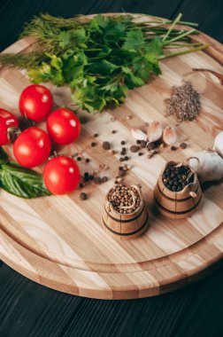 Baharatlar: kırmızı biber, kara biber, sarımsak, kimyon, kişniş, tatlı biber yalan bir kahverengi ahşap tahta siyah bir tablo üzerinde yuvarlak. Metnin altında yer