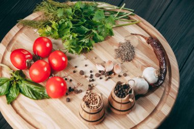 Baharatlar: kırmızı biber, kara biber, sarımsak, kimyon, kişniş, tatlı biber yalan bir kahverengi ahşap tahta siyah bir tablo üzerinde yuvarlak. Metnin altında yer