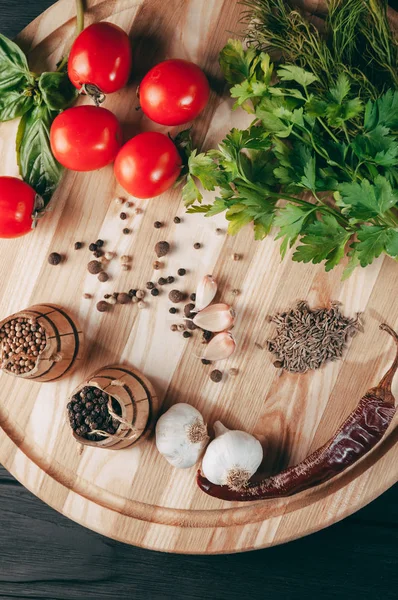 Baharatlar: kırmızı biber, kara biber, sarımsak, kimyon, kişniş, tatlı biber yalan bir kahverengi ahşap tahta siyah bir tablo üzerinde yuvarlak. Metnin altında yer