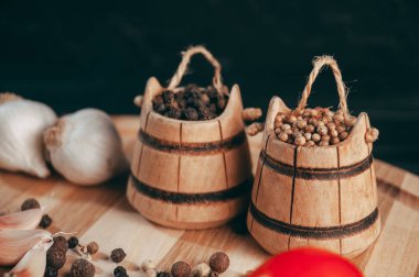 Baharatlar: kırmızı biber, kara biber, sarımsak, kimyon, kişniş, tatlı biber yalan bir kahverengi ahşap tahta siyah bir tablo üzerinde yuvarlak. Metnin altında yer