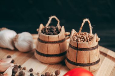 Baharatlar: kırmızı biber, kara biber, sarımsak, kimyon, kişniş, tatlı biber yalan bir kahverengi ahşap tahta siyah bir tablo üzerinde yuvarlak. Metnin altında yer