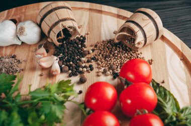 Baharatlar: kırmızı biber, kara biber, sarımsak, kimyon, kişniş, tatlı biber yalan bir kahverengi ahşap tahta siyah bir tablo üzerinde yuvarlak. Metnin altında yer