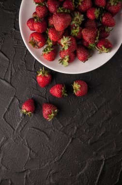 Siyah arka planda taze çilekler.