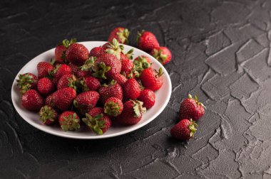 Siyah arka planda taze çilekler.