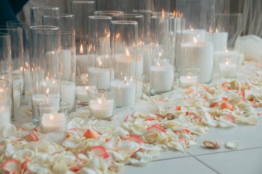 Düğün süslemeleri. Cam şişeler dağınık gül yaprakları ile birçok mum. Yan görünüm.