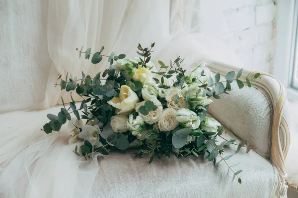 Belo buquê de casamento de rosas brancas e orquídeas em um velho sofá branco clássico . — Fotografia de Stock